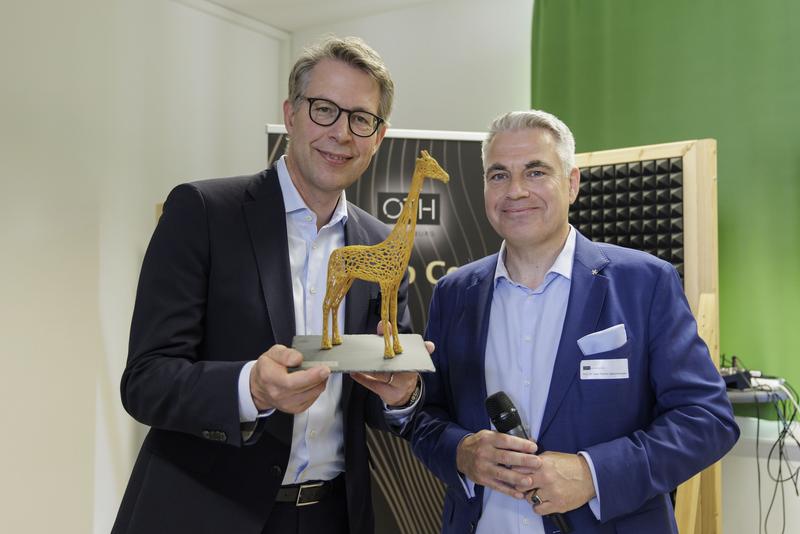 Prof. Dr. Sean Patrick Saßmannshausen (rechts), Leiter des Start-up Centers, überreichte Wissenschaftsminister Markus Blume die Gründungsgiraffe "Raphi", das Maskottchen des Start-up Centers.