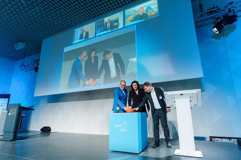 Bundesforschungsministerin Dorothee Bär, Prof. Andreas Tünnermann, Sprecher der QuNET-Initiative, und Prof. Christoph Marquardt, wissenschaftlicher Leiter der Live-Demonstration in Berlin, schalten Quantenkryptografie-Systeme zu einem Netz zusammen. 