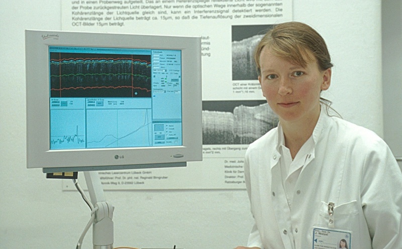 Priv.-Doz. Dr. med. Julia Welzel neben einem Monitor, auf dem eine OCT-Untersuchung der Haut sichtbar gemacht wurde