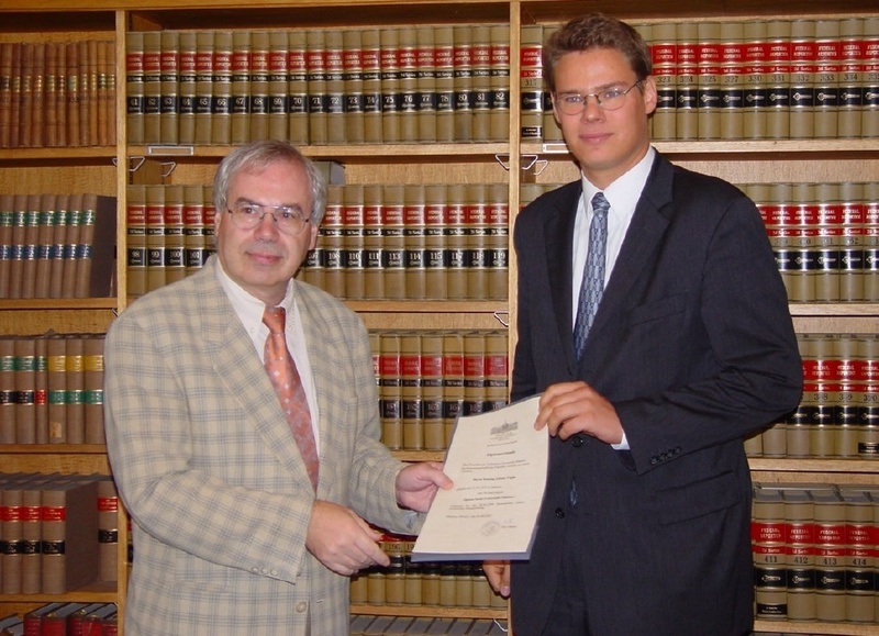 Henning Tappe (rechts) erhält von Jura-Dekan Prof. Dr. Wolfram Timm seine Diplom-Urkunde.
