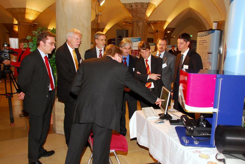 In der Ausstellung der Forschungsverbünde konnte Dr. Markus Lankers mit dem "Bio Particle Explorer" ein marktfähiges Gerät als Ergebnis der Förderinitiative präsentieren. V. l. n .r.: Prof. Dr. Jürgen Popp (Sprecher des Forschungsschwerpunktes Biophotonik), Prof. Dr. Frieder Meyer-Krahmer (Staatssekretär des BMBF), Dr. Hans Eggers (BMBF, Referat 513 "Optische Technologien),  Dr. Wolfram Eberbach (Abteilungsleiter im Thüringer Kultusministerium), Dr. Albrecht Schröter (Oberbürgermeister der Stadt Jena), Prof. Dr. Hans-J. Schwarzmaier (VDI-Technologiezentrum), Dr. Frank Stietz (Carl Zeiss AG). 