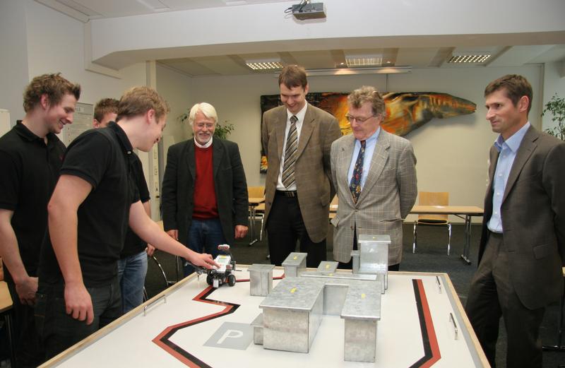 Wie bewältigt ein Roboter den Parcours durch ein Stahlwerkmodell? Gespannt beobachten die Kooperationspartner (von rechts), Prof. Dr. Karsten Morisse, Dr. Klaus Lang und  Christian Bloom (hier mit dem Leiter der Realschule Georgsmarienhütte Rudolf Meyer) die Demonstration der Auszubildenden der GMH.