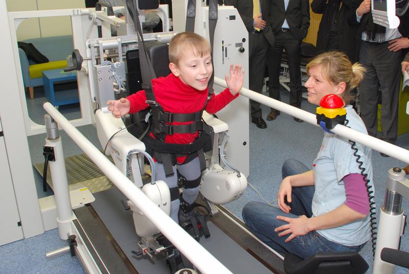 Der 6-jährige Kai Jersch bei einer Therapieeinheit auf dem Lokomaten. Physiotherapeutin Alexandra Bayer steuert per Computer die "Gangorthese", die dem Jungen beim Gehen hilft.