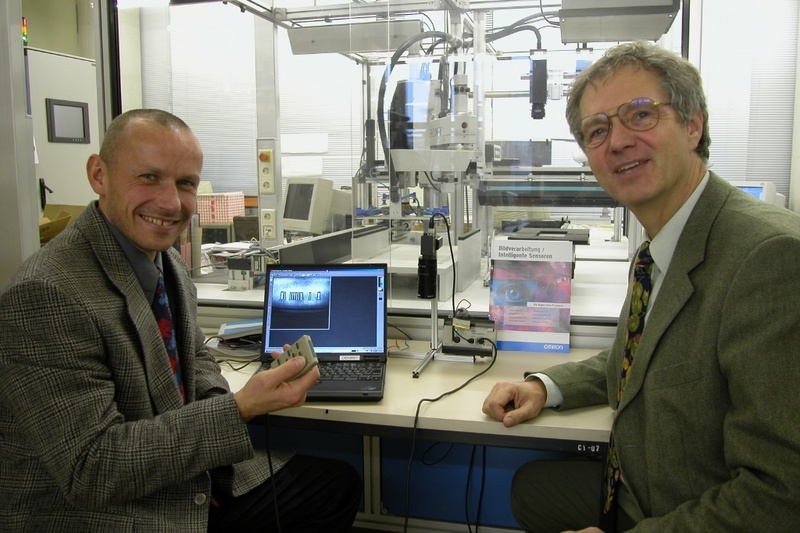 OMRON-Mitarbeiter Torsten Schellschmidt (l.), erläutert FH-Rektor Prof. Dr. Dudziak das Bildverarbeitungssystem.