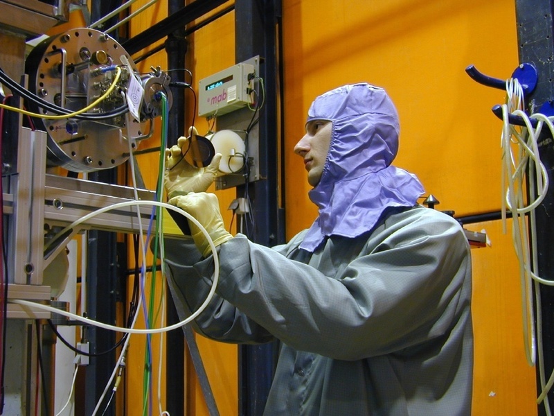 Der RUB-Physiker Vladimir Tschernychev im Reinraumanzug mit einer der Lochmasken an der Ionenprojektionsanlage des Dynamitron-Tandem-Labors.