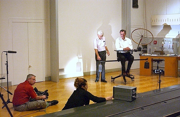Das Prinzip des Kreiselkompasses wird mit Hilfe eines Speichenrades auf einem Drehstuhl demonstriert