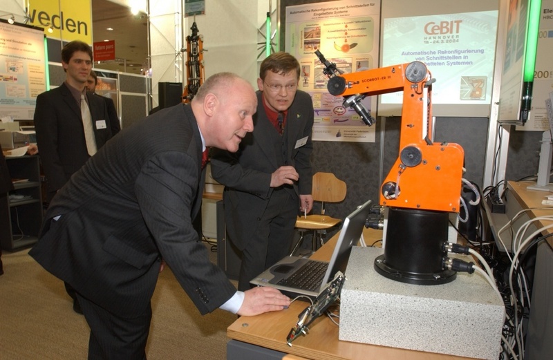 Prof. Dr. Wolfram Hardt von der Professur Technische Informatik der TU Chemnitz (r.) erläutert Ministerpräsident Georg Milbradt, wie zwischen den Modulen eines Industrieroboters Daten ausgetauscht werden können. Foto: FfdZ, Peter Schmalfeldt