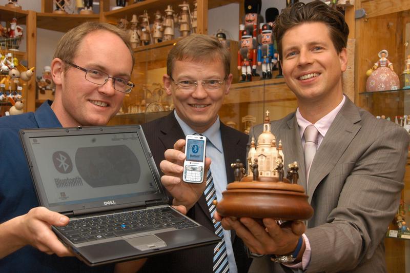 Mirko Caspar und Prof. Dr. Wolfram Hardt (v.l.) von der TU Chemnitz übergeben die elektronische Spieldose an Ringo Müller von der Kleinkunst aus dem Erzgebirge Müller GmbH. Egal ob mit dem Laptop oder dem Handy - per Bluetooth können auf diese Spieldose immer neue Melodien übertragen werden.