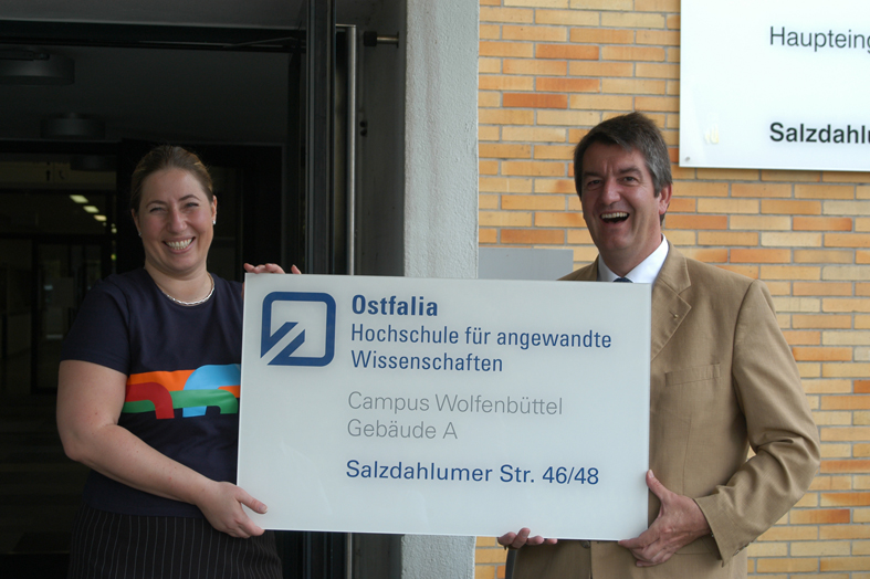von links: Vera Huber, zuständig für das Corporate Design der Ostfalia, und Vizepräsident Volker Küch halten das  neue Haupteingangsschild für den Campus Wolfenbüttel in Händen.